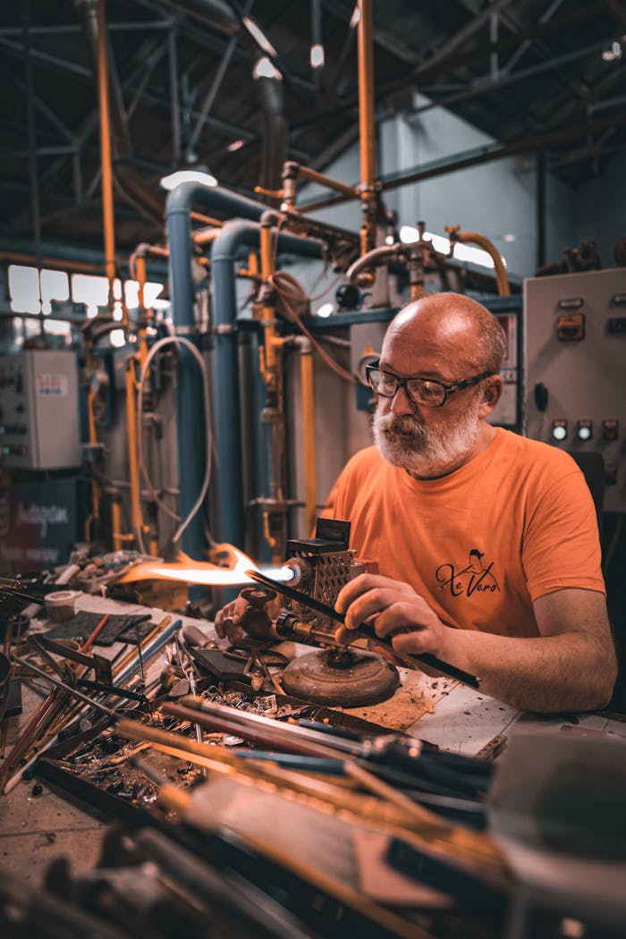 Elderly man meticulously working in a glassblowing factory in Burano, Italy.